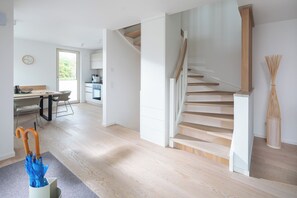 A modern interior with a staircase, a dining area, and a kitchen. - // DUNE NEIGHBORHOOD NO. 1 // (Norderney)