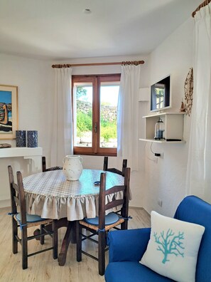 A dining area with a round table, chairs, a white pitcher, and a blue sofa with a tree-patterned pillow. - A stone's throw from the sea! (Cannigione)