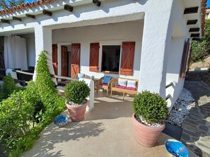 A covered outdoor seating area with wicker furniture and potted plants. - A stone's throw from the sea! (Cannigione)