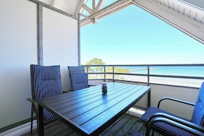 A balcony with a table and chairs, a view of the sea, and a clear sky. - Residence Ostseestrand Apartment 29 (Scharbeutz)