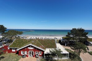 A coastal building with a green roof, a pier in the background, and a beach. - Residence Ostseestrand Apartment 29 (Scharbeutz)