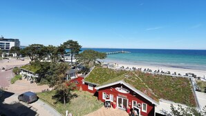 Ein Küstenhotel mit einem roten Gebäude, einem grünen Dach und einer Pier im Hintergrund.