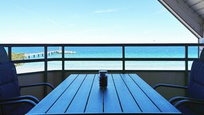 Ein Balkon mit Blick auf das Meer, einem Holztisch und zwei Stühlen.