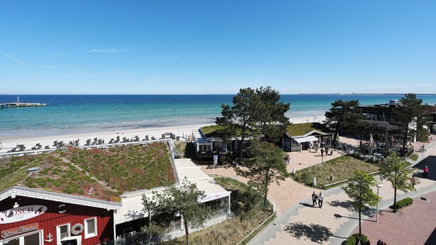 Ein Hotel an der Küste mit Blick auf den Strand, ein rotes Gebäude und ein gepflasterter Weg.