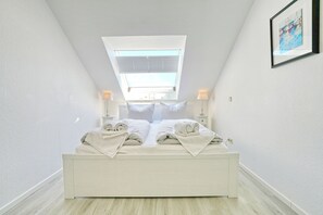 A bedroom with a skylight, a bed with pillows and towels, bedside lamps, and a framed picture on the wall. - Residence Ostseestrand Apartment 29 (Scharbeutz)