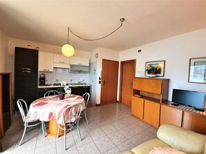 A compact living space with a dining area, kitchenette, and a sofa. - Cozy apartment 5 minutes from the beach with private parking (Veneto)