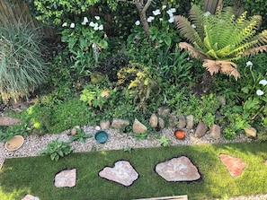 A garden with various plants, rocks, and a small pond.