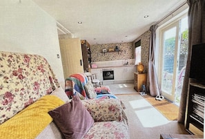 A living room with a sofa, a fireplace, a kitchen area, and a large window.