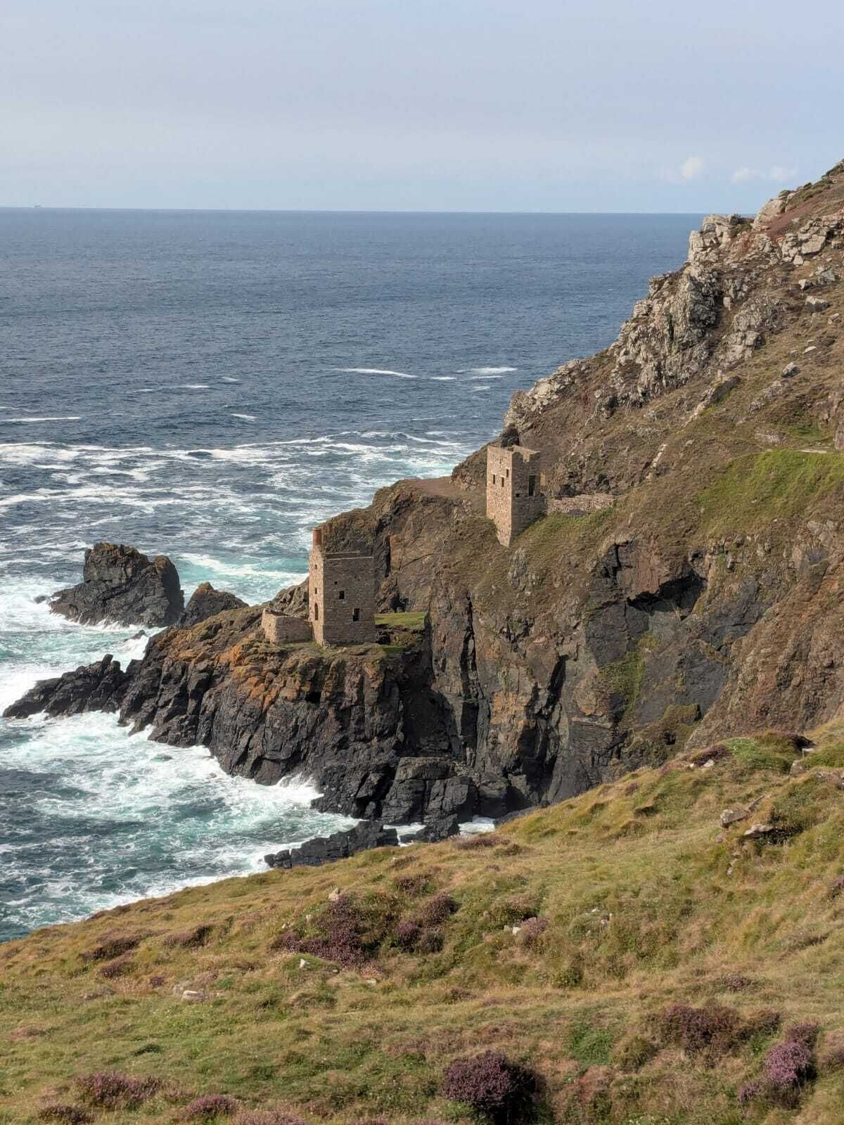 Une falaise côtière surmontée d’une structure en pierre d’époque, qui offre une vue sur la mer.