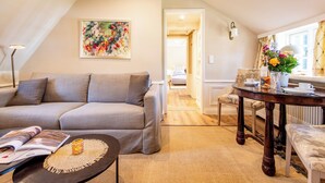 Ein modernes Wohnzimmer mit grauem Sofa, einem Couchtisch, einem Esstisch mit Stühlen und einem Bild an der Wand.