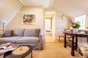 Uma sala de estar moderna com um sofá cinzento, uma mesa de centro, uma mesa de jantar com cadeiras e um quadro na parede.