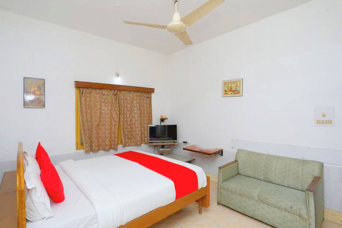 Una habitación con cama, televisor, sofá y ventilador de techo.