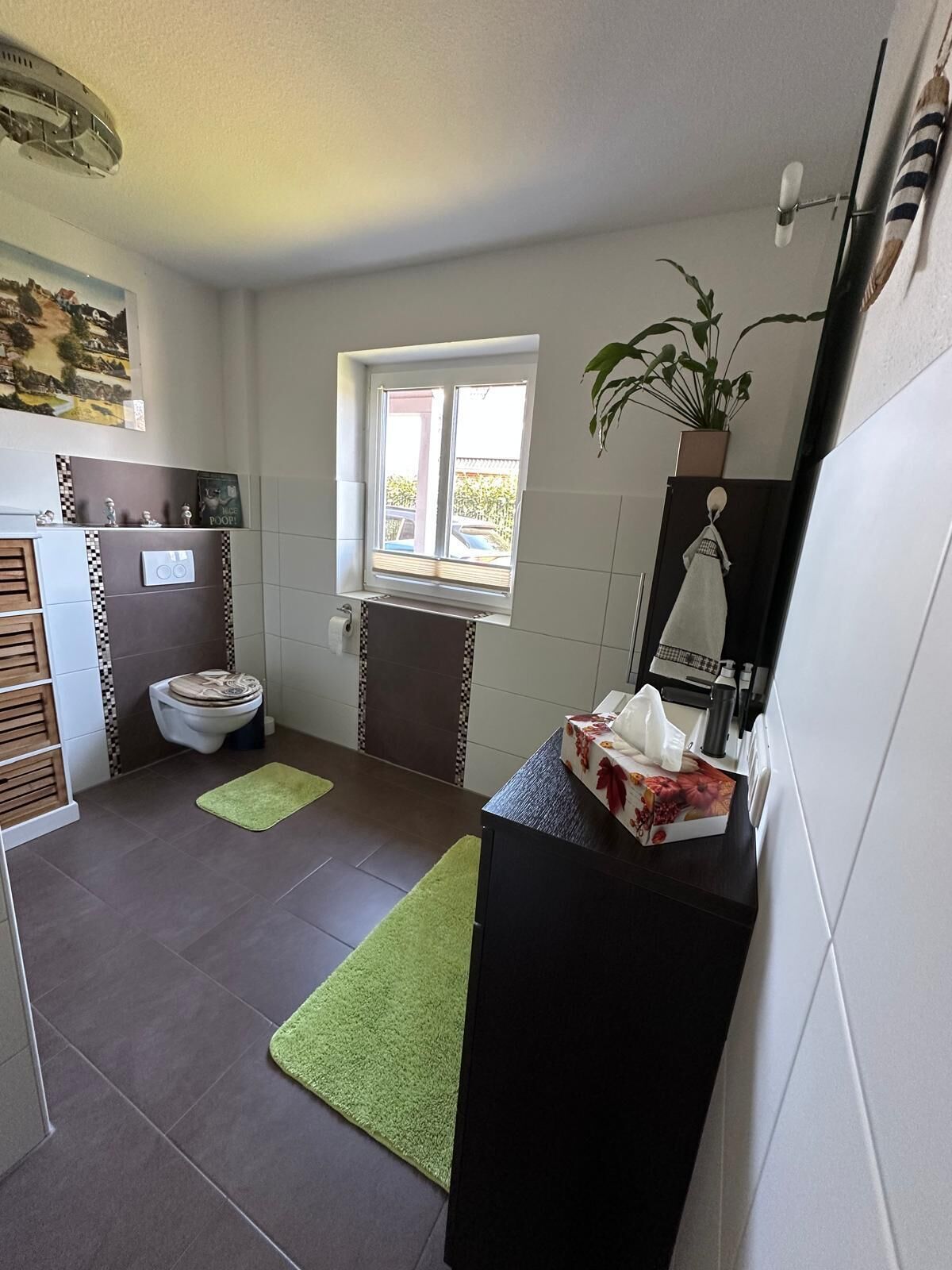 A bathroom with a toilet, bidet, towel rack, and a window.