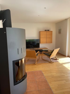 A modern living room with a black refrigerator, wooden cabinet, and a flat-screen TV.