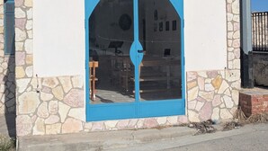 Ein kleines Gebäude mit einer steinernen Fassade, einer blauen Tür und einem Kreuz auf dem Dach.