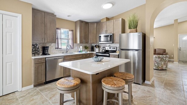 A kitchen with a central island, stainless steel appliances, and wooden cabinets. - Seabreeze- Private Pool and just steps to Beach (St. Augustine Beach)