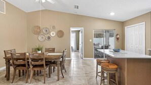 A spacious kitchen with a dining area, a ceiling fan, and a view into the backyard. - Seabreeze- Private Pool and just steps to Beach (St. Augustine Beach)