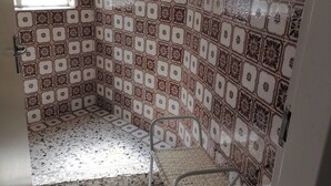 A room with patterned tile walls, a metal chair, and a window.