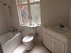 A bathroom with a toilet, a bathtub, a sink, and a window with a decorative item. - Room-charming B&B Retreat in Viljoenskro (Moqhaka)
