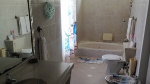 A bathroom with a large mirror, a sink, a toilet, and a bathtub.