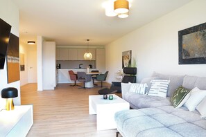Un salon moderne avec un canapé gris, une table basse et un coin repas comprenant des chaises et une table.