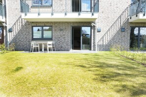 Un bâtiment moderne avec une façade en briques, un balcon et un petit espace extérieur aménagé avec des chaises.