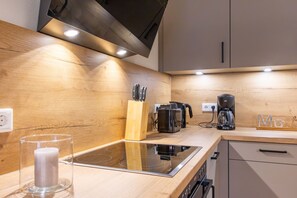A modern kitchen with a wooden countertop, a glass stovetop, a coffee maker, and a knife block. - Vacation apartment Hyggehuus Tossens - Balcony. Sauna. Close to the beach. (Tossens)