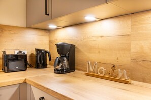 A kitchen with a toaster, coffee maker, and wooden wall. - Vacation apartment Hyggehuus Tossens - Balcony. Sauna. Close to the beach. (Tossens)