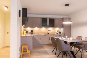 Une cuisine moderne avec des meubles en bois, une table à manger avec des chaises et un petit tabouret.