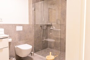 Une salle de bain moderne avec une douche à parois de verre, des toilettes et un lavabo.