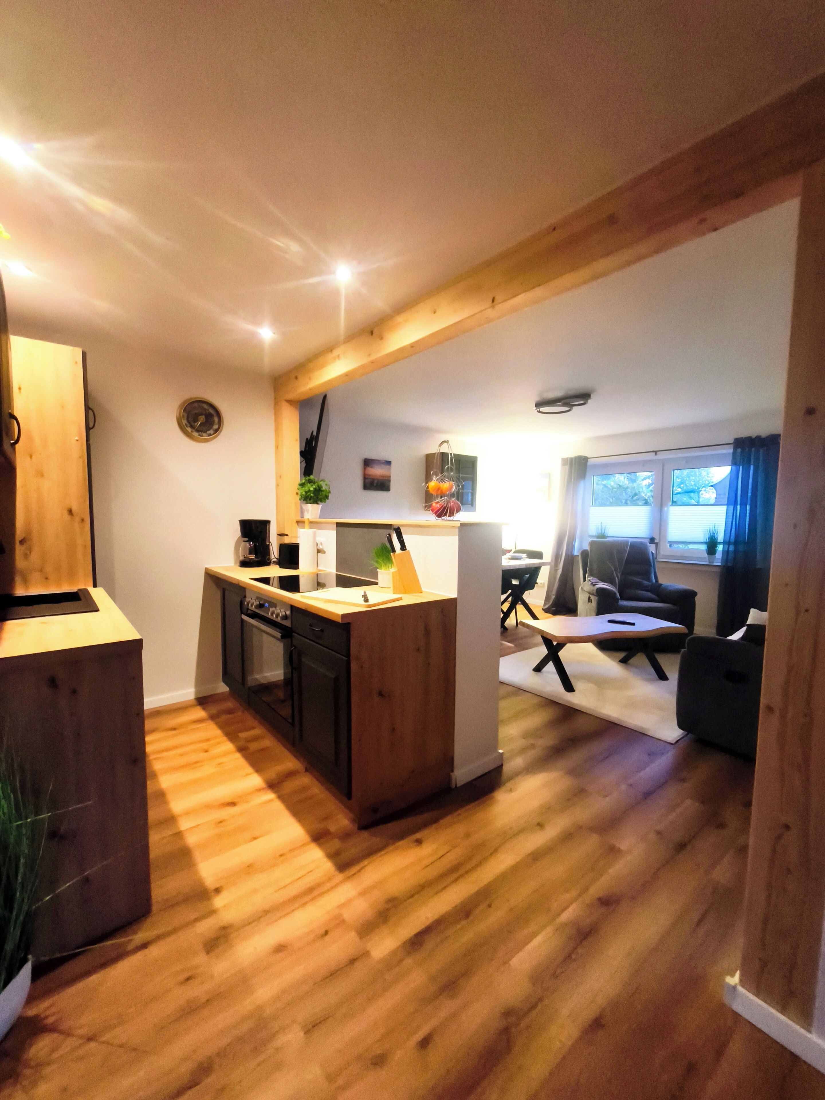 Eine moderne Küche mit Holzausstattung, einer zentralen Kochinsel und einem Essbereich mit Tisch und Stühlen.
