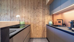 A modern kitchen with wooden paneling, a green toaster, a sink, and a kettle. - MOAHOF Chalets & Appartements (Wagrain)