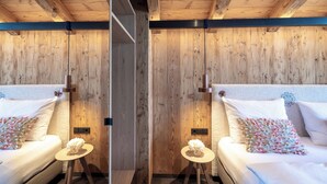 A mirrored room with wooden walls, a bed with white bedding, and a small round table with a vase of flowers. - MOAHOF Chalets & Appartements (Wagrain)