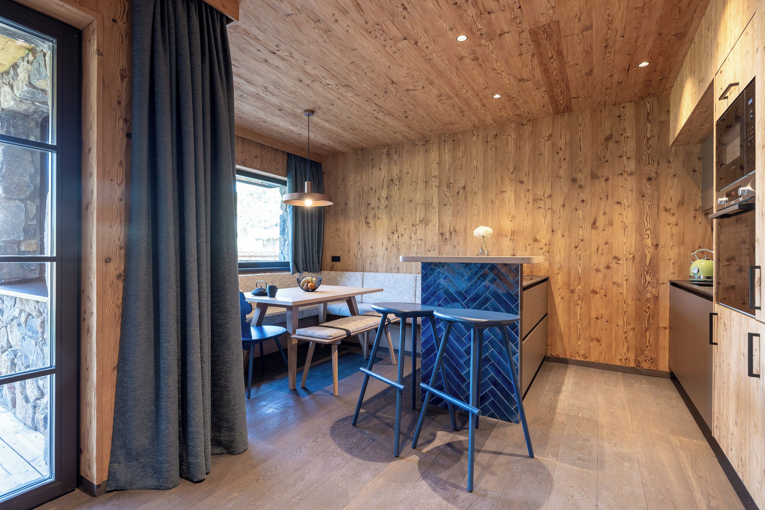 Une cuisine moderne avec des murs en bois, un coin bar et un espace repas comprenant une table et des chaises.