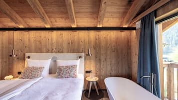 A wooden cabin bedroom with a bed, bedside tables, and a view of the outdoors.