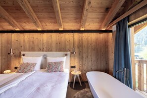 Quarto de cabana de madeira com uma cama, mesas de cabeceira e vista para o exterior.