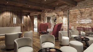 A modern interior with wooden beams, brick walls, and a mix of red and white upholstered chairs. - MOAHOF Chalets & Appartements (Wagrain)