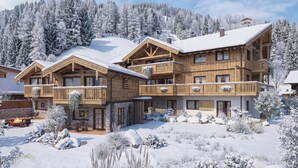 A multi-story wooden lodge with balconies, stone foundation, and a snow-covered landscape. - MOAHOF Chalets & Appartements (Wagrain)