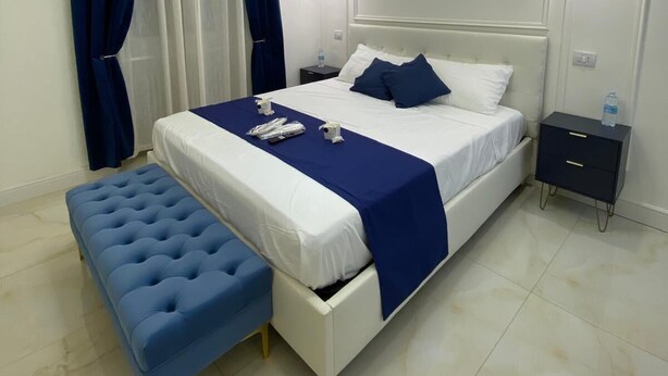 A modern bedroom with a large bed, a bedside table, a bench, and a unique circular light fixture. - Suites within walking distance of Lake Como (Como)