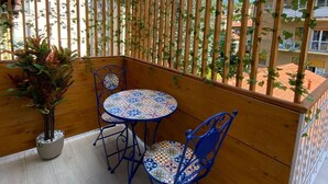A wooden balcony with a tiled table and chairs, a potted plant, and a view of buildings. - Suites within walking distance of Lake Como (Como)