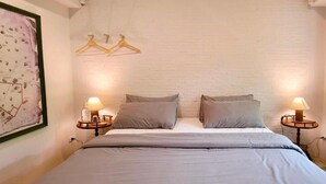 A bedroom with a bed, two bedside tables, two lamps, a wall-mounted light fixture, and a framed picture on the wall. - Ena Boutique Hotel & Cafe (Chiang Mai)