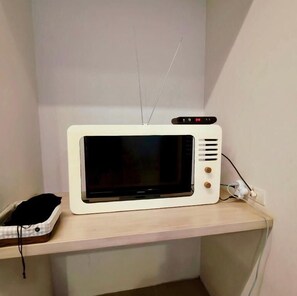 Un microondas blanco sobre una repisa de madera en una habitación.