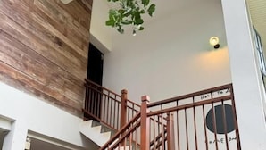A multi-level building with a wooden staircase, a white exterior, and a hanging plant. - Ena Boutique Hotel & Cafe (Chiang Mai)