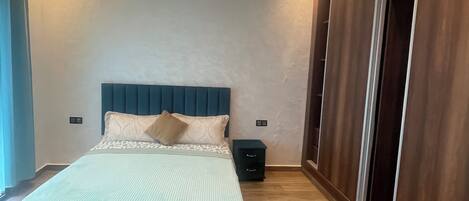 A bedroom with a bed, bedside tables, a wardrobe, and a ceiling light fixture.