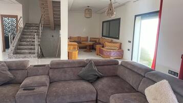 Una sala moderna con un sofá modular, una mesa de centro, una escalera y un comedor.