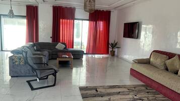 Una sala de estar amplia con sofá, una butaca, una mesita de centro y un tapete decorativo.