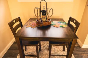 Une table de salle à manger en bois, avec une bouteille de vin de San Gimone, un plateau en bois et deux sets de table décoratifs.