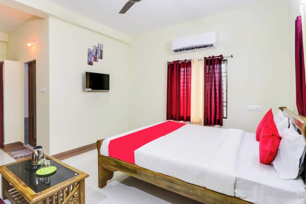 Une chambre d’hôtel équipée d’un lit, d’une télévision, d’un climatiseur et d’une fenêtre avec des rideaux.