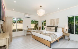 A modern bedroom with a large bed, a desk, and a chair, featuring large windows and a ceiling light. - Fox Eden Resort; 8bd, Pool& Spa Oasis (Fort Lauderdale)