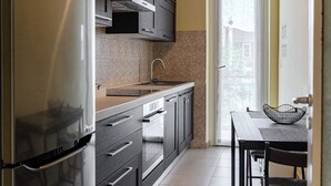 Een keuken met een ingebouwde oven, een spoelbak en een eethoek met tafel en stoelen.